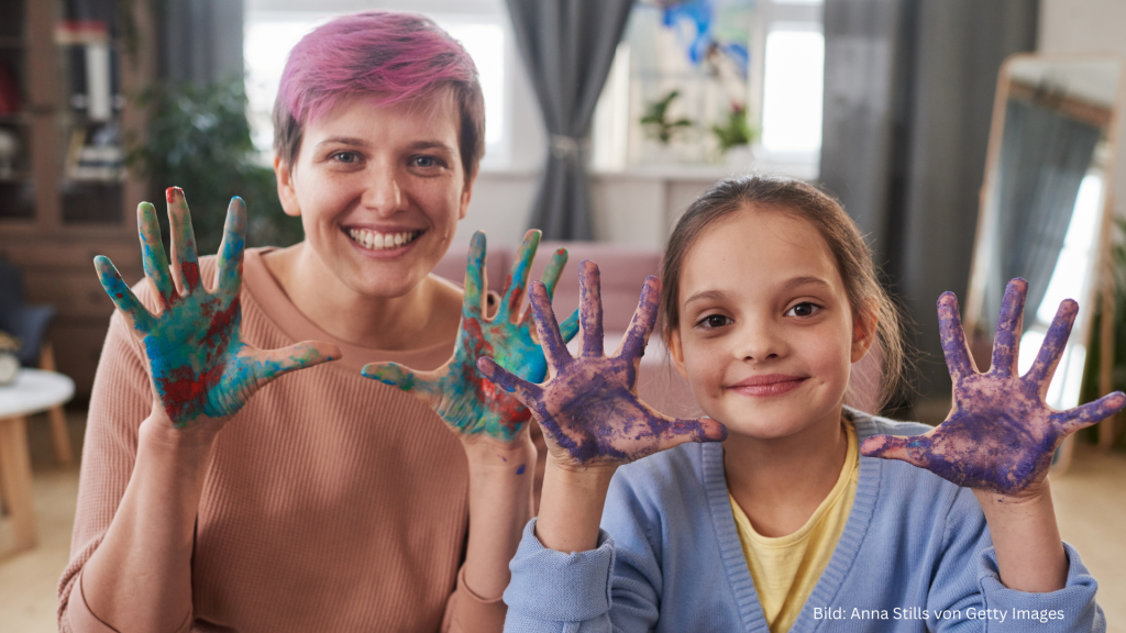 Lächelnde Mama und Tochter mit bemalten Händen
